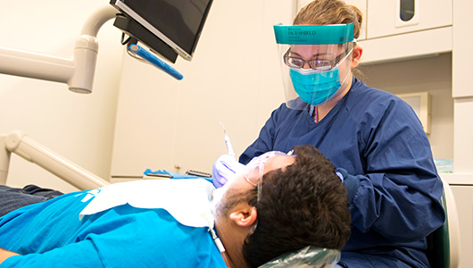FSC dental hygienist works on a patient.