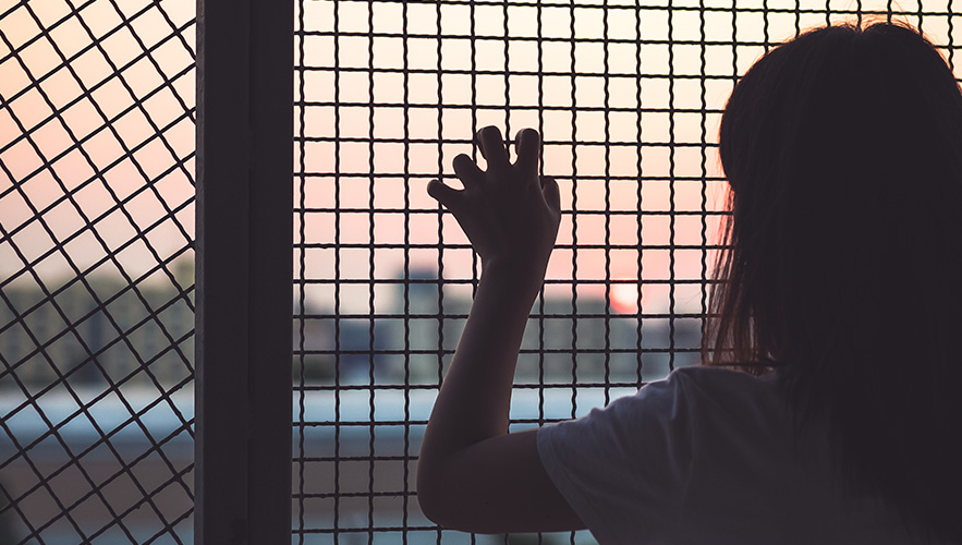 girl behind a wire fence