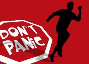 A stop sign with text "Don't panic" with a black outline of a person running away.