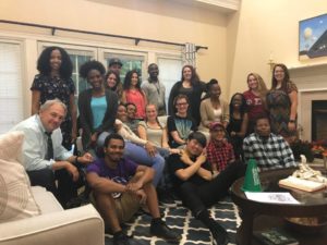 Students sitting in a living room taking a group photo.