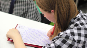 Student sitting at desk writing an essay.